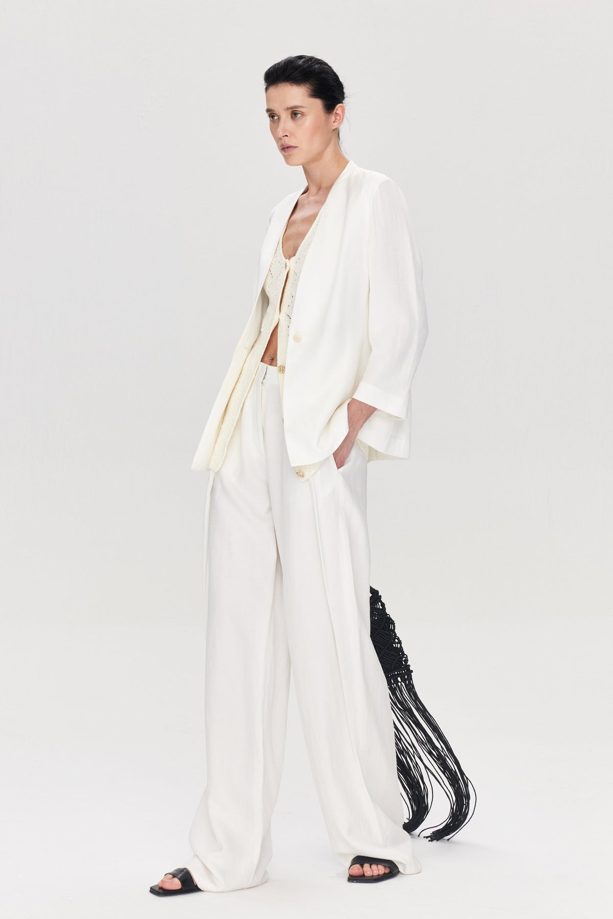 Woman wearing a white outfit with black accents on a plain background